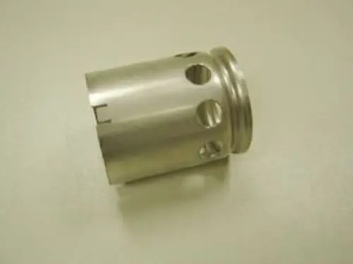 Metallisches Bauteil mit mehreren Öffnungen und einem abgerundeten oberen Rand, möglicherweise Teil eines Heizungs- oder Lüftungssystems von Remeha.